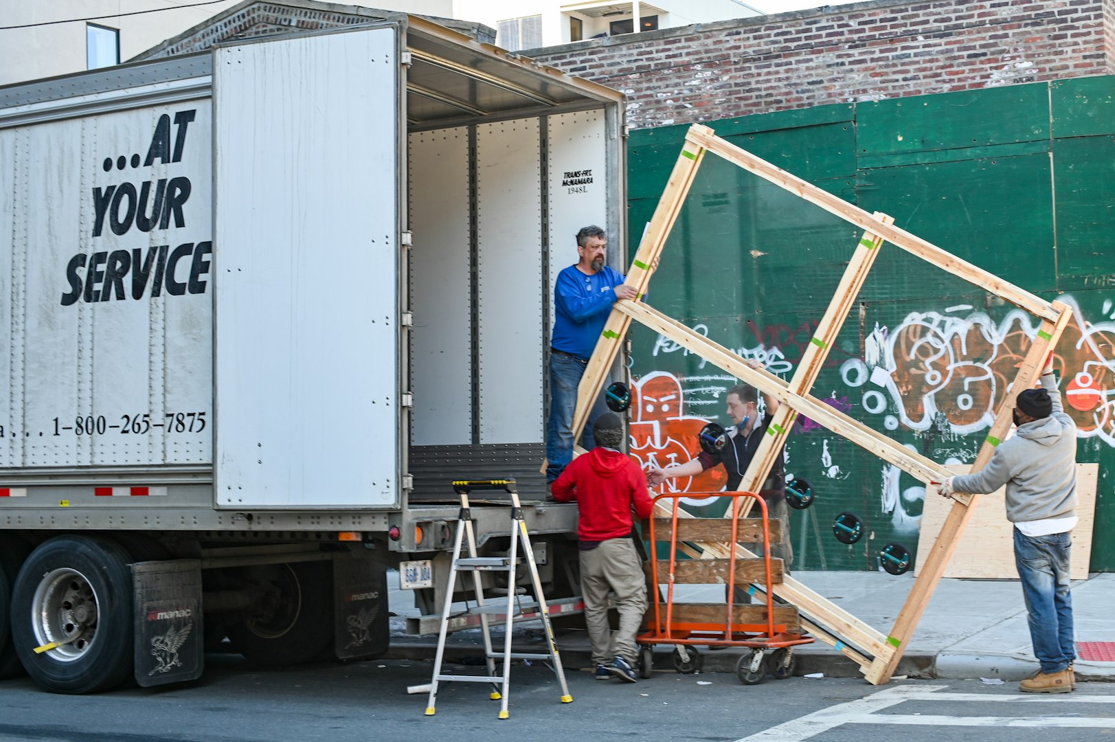 a man in a yellow safety vest and green gloves unloads a garbage bag